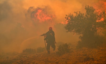 A firefighter runs away from flames while trying to extinguish a wildfire