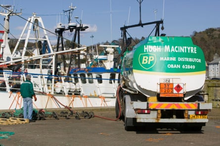 A fuel tanker on a quayside with a pipe leading to a fishing boat