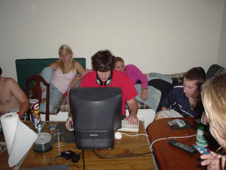 A group of young people, some sitting at computers, others lounging on sofas in the background