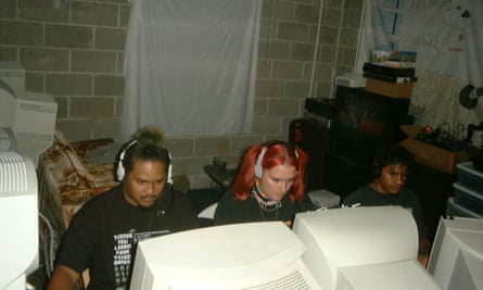Three people sitting at computers in a space that could be a garage
