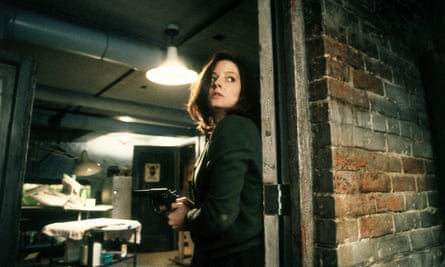 As Clarice Starling in The Silence of the Lambs. She is holding a gun and hiding behind a brick wall.