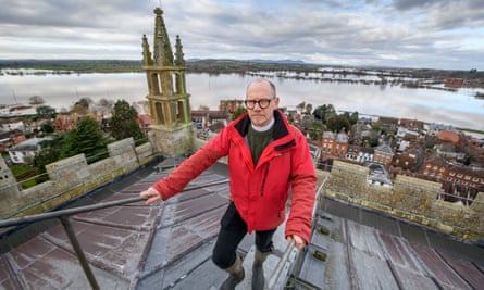 The Rev Nick Davies, pictured here on the tower of Tewkesbury Abbey, with the flood waters behind him