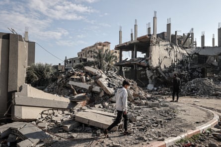 Palestinians next to the rubble of a buildings destroyed by Israeli attacks in Deir al-Balah, Gaza on 5 January 2024.