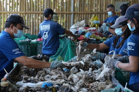 People with masks sorting through plastic waste