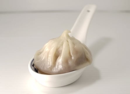 A Xiao Long Bao dumpling on a white porcelain spoon