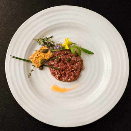 steak tartare on a white plate with garnish