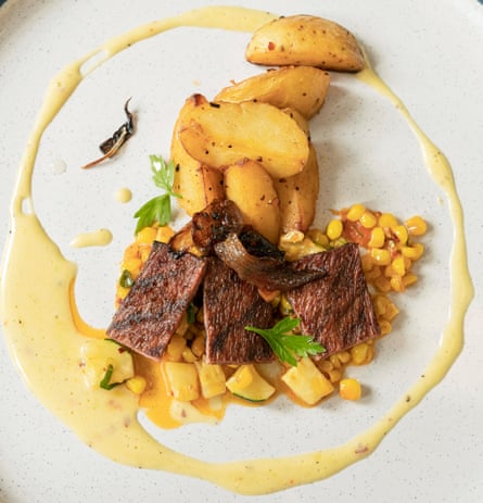 Lab-grown steak on a plate with chips and sweetcorn and garnish
