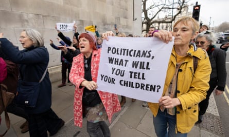 Singing protesters walk along a footpath, with two women holding a banner reading: ‘Politicians, what will you tell your children?’