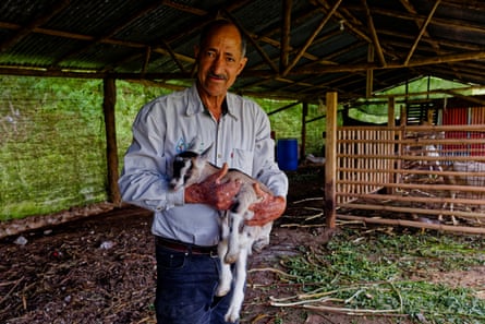 Esteban Polanco smiling and holding a young goat in an open barn