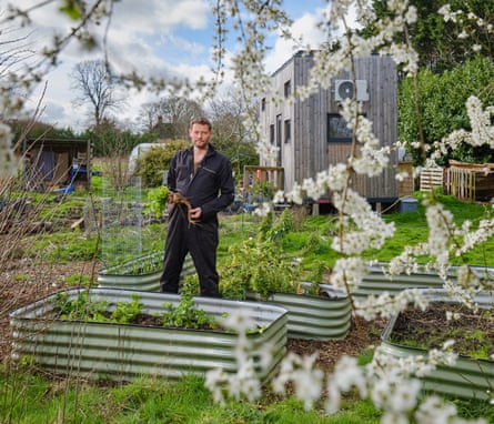 James Campbell in the field in front of his tiny off-grid home in Essex, England