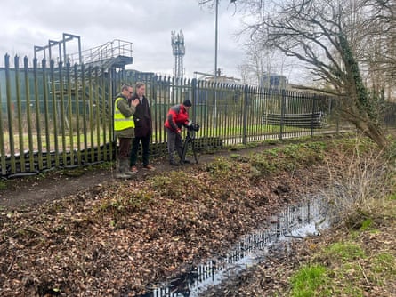 Three people stand inside perimeter fence of Horley sewage treatment works