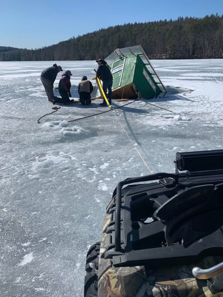 small house has fallen partway through the ice - four people gather around it