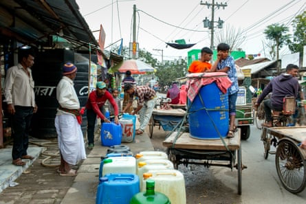 A market stall with rows of water butts and a large barrel on a cart
