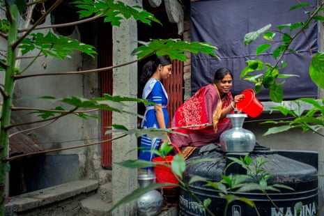 Shopna Dhali with her daughter pouring drinking water from a tank in front of their house in Dacope, Khulna, Bangladesh, 2024.