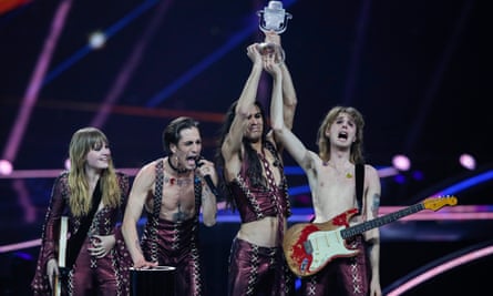 Two members of a four-piece band on stage hold aloft a trophy