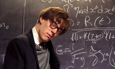 In glasses, in front of a blackboard covered in equations