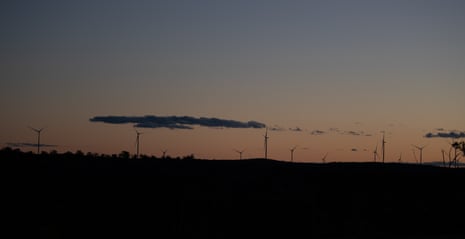 The MacIntyre windfarm project by night, turbines silhouetted against a setting sun.