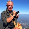 Jon Nicholson with camera atop a high mountain