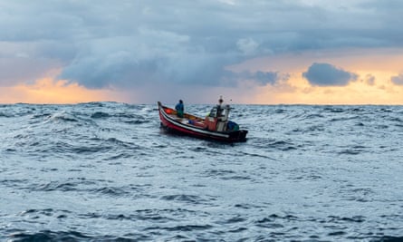 A boat with two people in it on the open sea. 