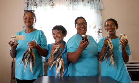 Four women holding up small fish and pantry items. 