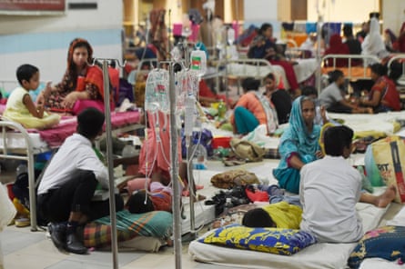 Children attached to drips lying on hospital beds and mattresses on the floor amid a crowded scene of south Asian adults and children