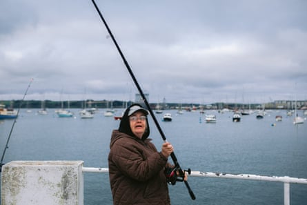 A woman in a warm coat and hat holding a fishing rod