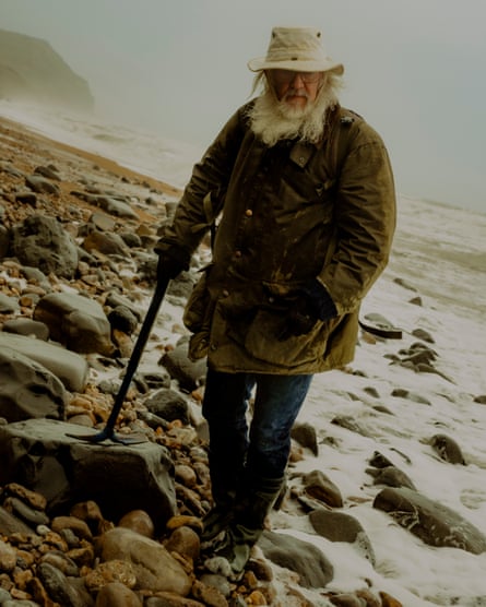 Richard Forrest walks across the beach carrying a pick, used for digging out rocks, especially shale and mudstones, which are relatively soft.